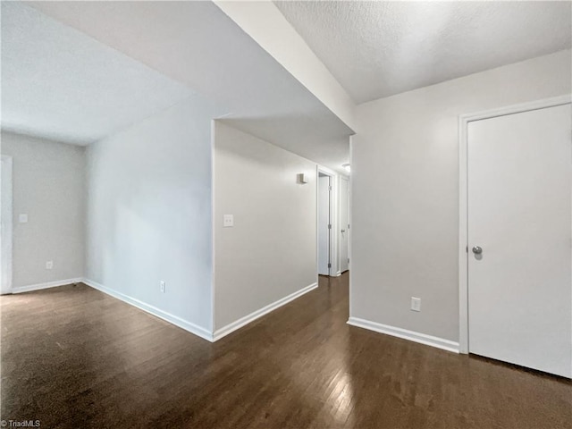 spare room featuring dark hardwood / wood-style flooring and a textured ceiling