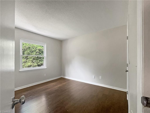 spare room featuring a textured ceiling and dark wood-type flooring