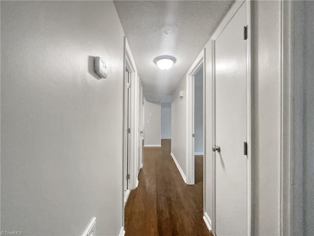 corridor featuring a textured ceiling and dark wood-type flooring