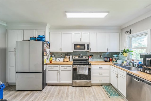 3121 Luther St, Winston-Salem, NC 27127 - kitchen with appliances with stainless steel finishes, wooden counters, light wood-type flooring, white cabinetry, and ornamental molding