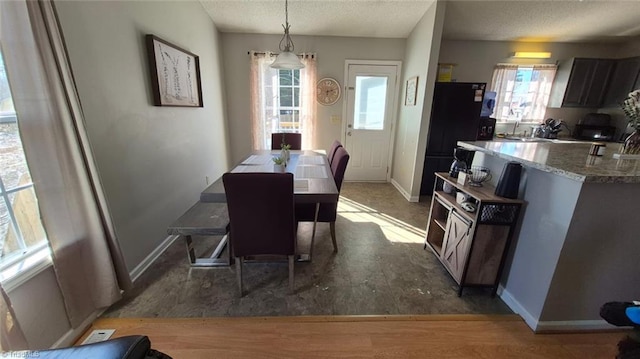 dining space with a textured ceiling, plenty of natural light, dark wood finished floors, and baseboards