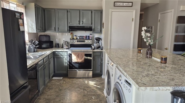 kitchen with light stone counters, under cabinet range hood, independent washer and dryer, gray cabinets, and black appliances