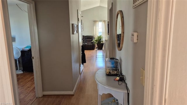 hall with lofted ceiling, baseboards, and light wood finished floors