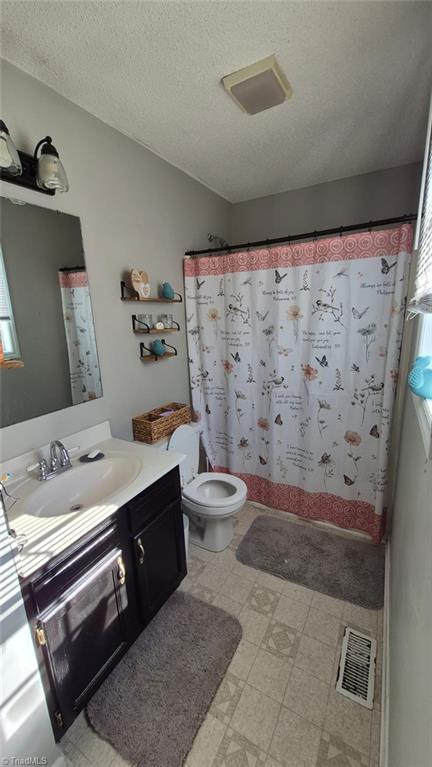 full bathroom featuring a textured ceiling, toilet, vanity, visible vents, and tile patterned floors