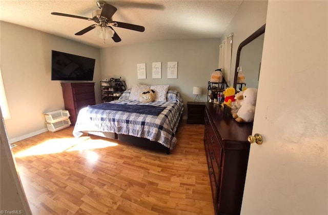 bedroom featuring light wood-style floors, a textured ceiling, baseboards, and a ceiling fan