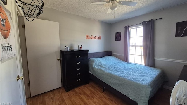 bedroom with a textured ceiling, a ceiling fan, and wood finished floors