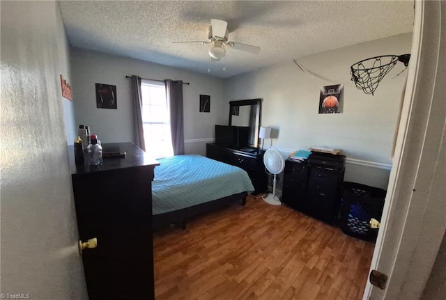 bedroom with a ceiling fan, a textured ceiling, and wood finished floors