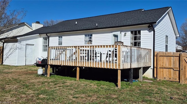 back of property with a lawn, a chimney, roof with shingles, fence, and a wooden deck