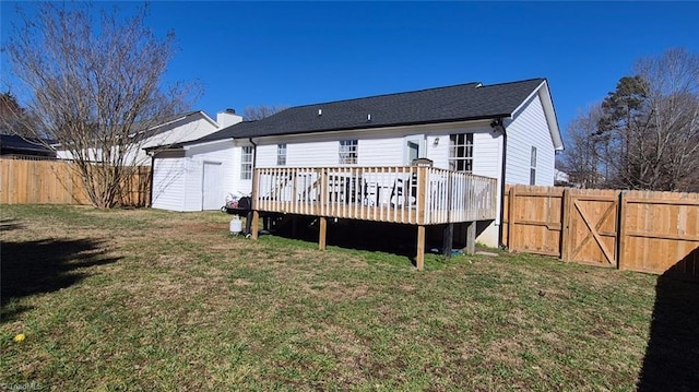 back of property with a deck, a lawn, a fenced backyard, and a gate