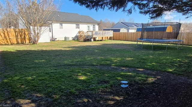 view of yard with a deck, a trampoline, a fenced backyard, and central air condition unit