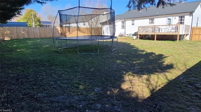 view of yard featuring a fenced backyard, a trampoline, and a wooden deck