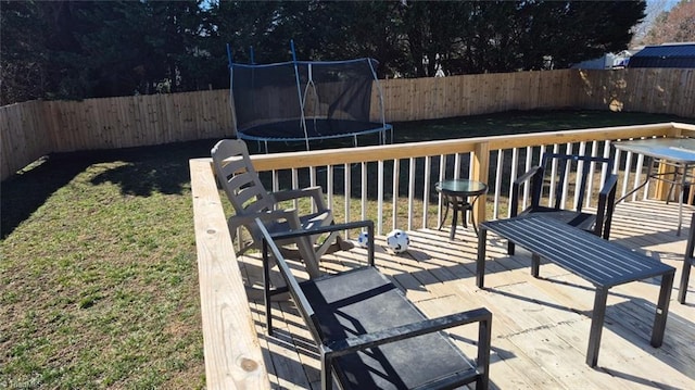 deck with a fenced backyard, a trampoline, and a yard