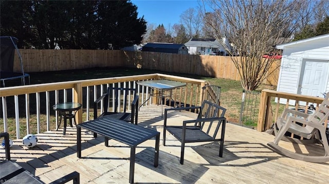 deck featuring a trampoline and a fenced backyard