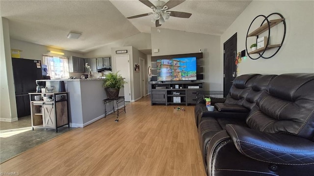 living area featuring light wood finished floors, lofted ceiling, ceiling fan, a textured ceiling, and baseboards