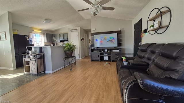 living room featuring lofted ceiling, a textured ceiling, light wood-style flooring, a ceiling fan, and baseboards