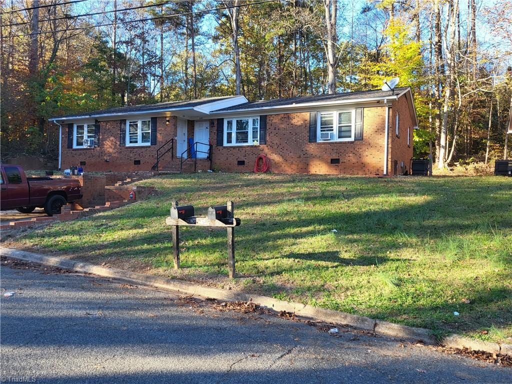 ranch-style house with central air condition unit and a front yard