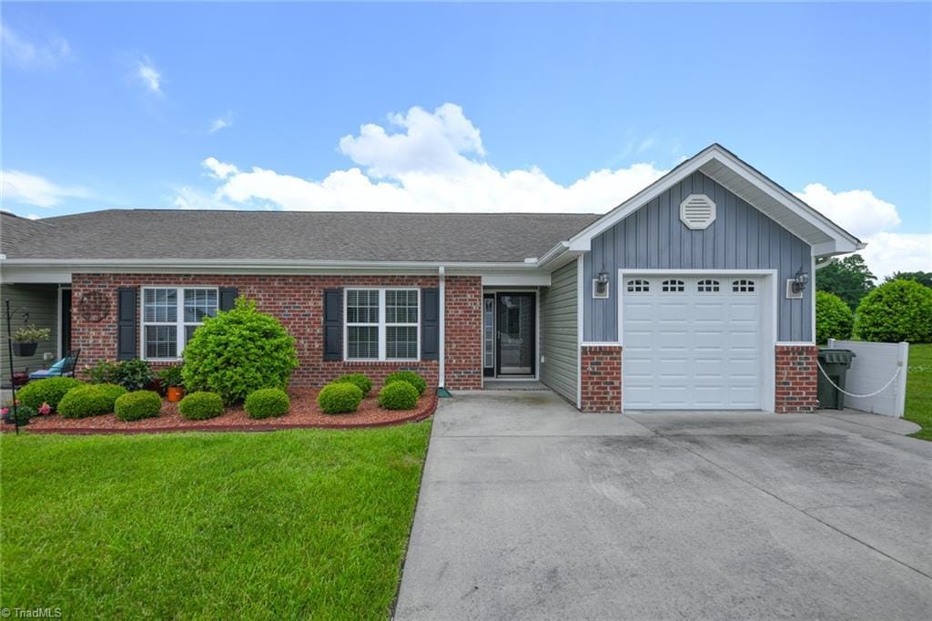 6702 Allendale Dr, Archdale, NC 27263 - ranch-style house with brick siding, board and batten siding, a garage, concrete driveway, and a front yard