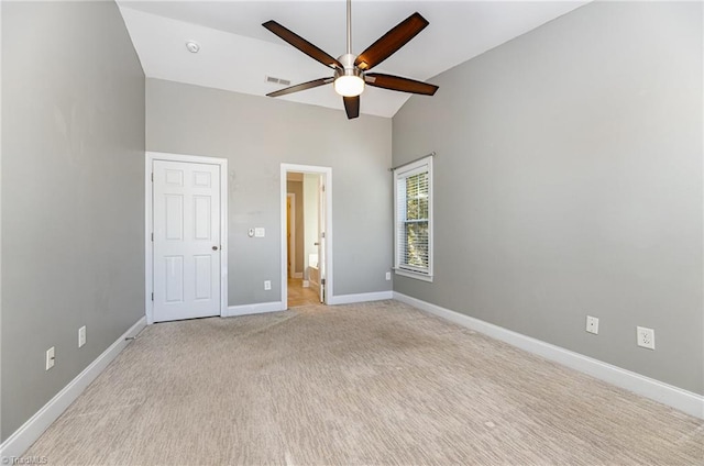 unfurnished bedroom featuring ensuite bathroom, high vaulted ceiling, light carpet, and ceiling fan