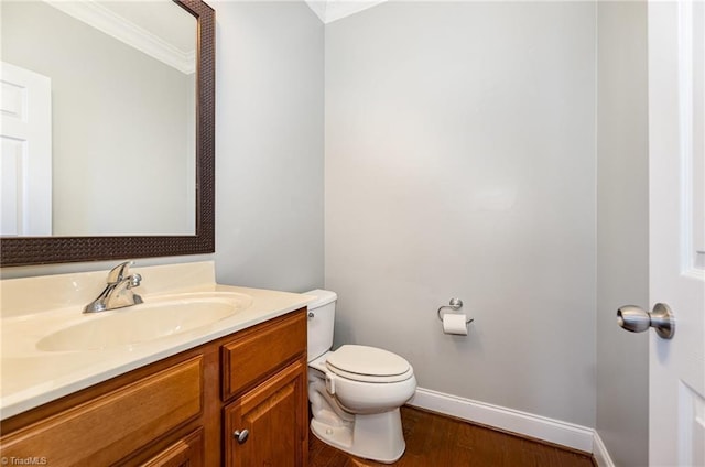 bathroom with hardwood / wood-style floors, toilet, ornamental molding, and vanity