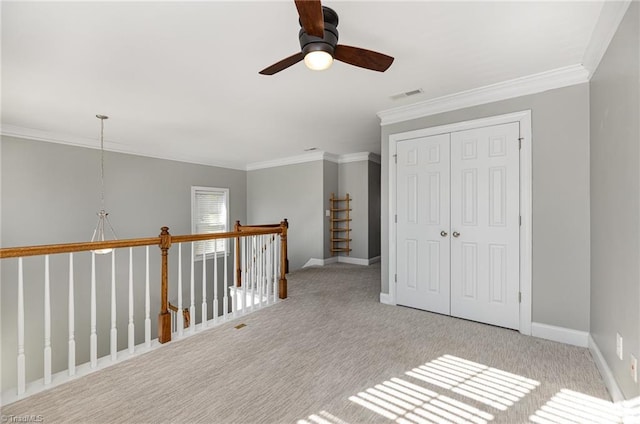 interior space with ceiling fan, ornamental molding, and light colored carpet