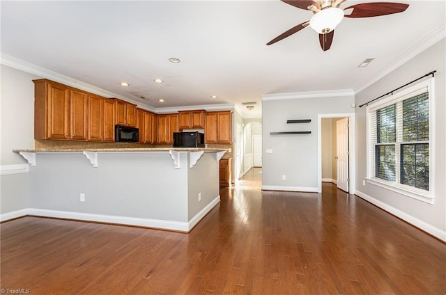 kitchen with black appliances, a breakfast bar, ornamental molding, and kitchen peninsula