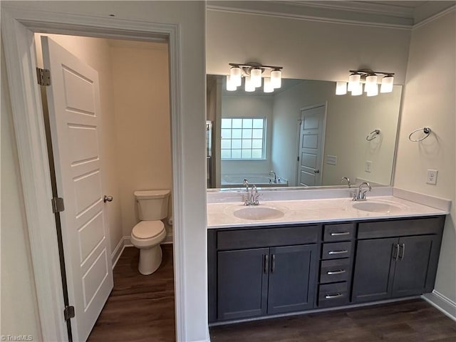 bathroom featuring hardwood / wood-style floors, a tub to relax in, ornamental molding, vanity, and toilet