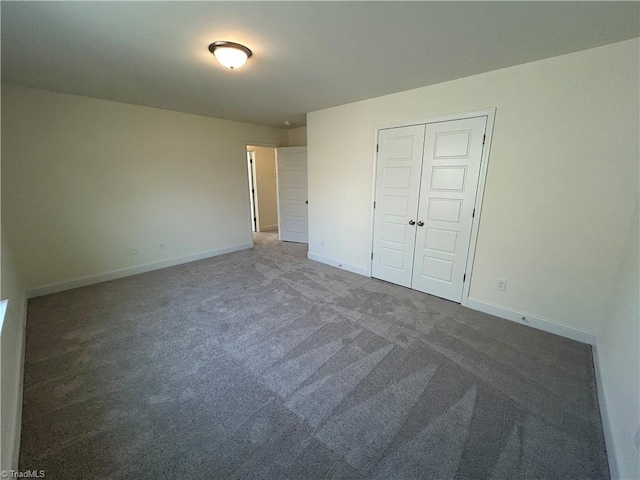 unfurnished bedroom with a closet and dark colored carpet