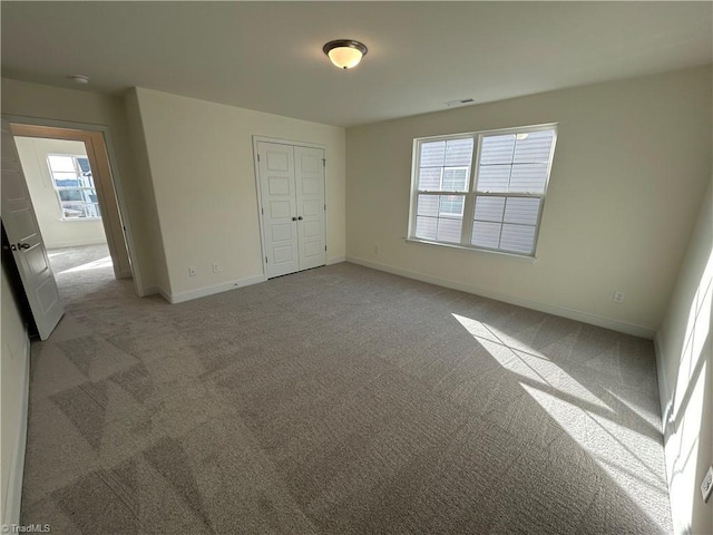 unfurnished bedroom with light carpet and a closet