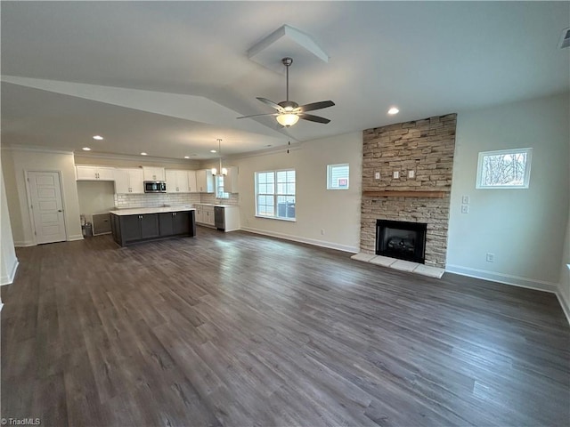 unfurnished living room with lofted ceiling, a stone fireplace, dark hardwood / wood-style floors, and ceiling fan