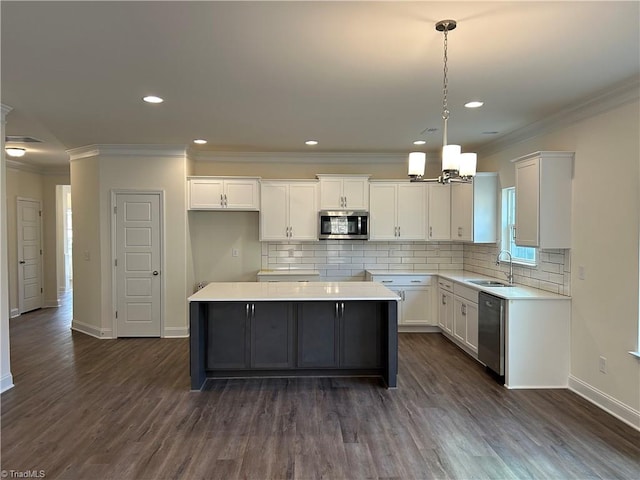 kitchen with white cabinetry, appliances with stainless steel finishes, decorative light fixtures, and a kitchen island