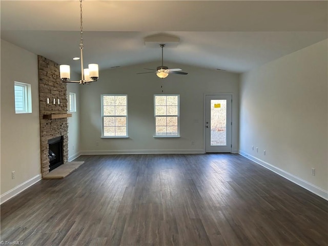 unfurnished living room featuring a stone fireplace, dark hardwood / wood-style floors, ceiling fan with notable chandelier, and lofted ceiling