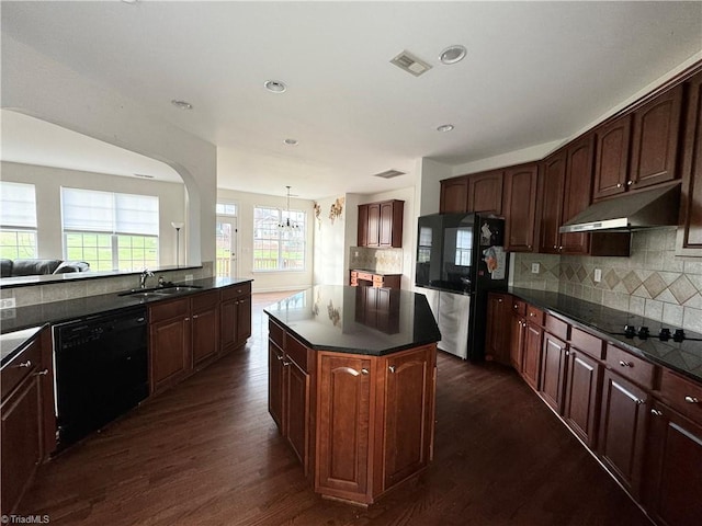 kitchen featuring sink, tasteful backsplash, dark hardwood / wood-style flooring, a kitchen island, and black appliances