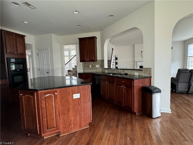 kitchen featuring kitchen peninsula, tasteful backsplash, sink, dark hardwood / wood-style floors, and a kitchen island