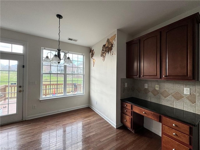 kitchen featuring pendant lighting, decorative backsplash, dark wood-type flooring, and built in desk