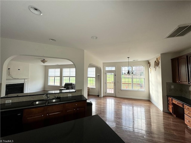 kitchen featuring decorative backsplash, dark brown cabinets, sink, an inviting chandelier, and hardwood / wood-style floors