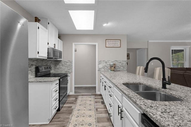 kitchen featuring white cabinetry, sink, stainless steel appliances, and light stone countertops