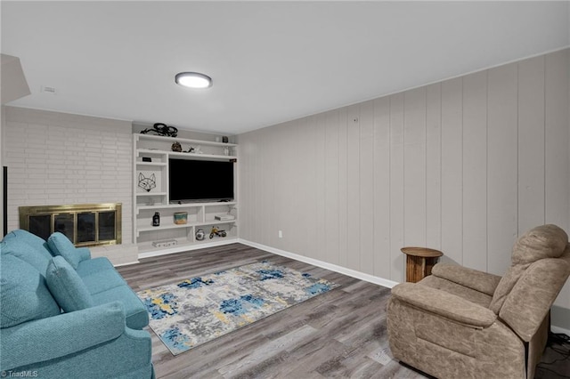 living room with wooden walls, wood-type flooring, a fireplace, and built in features