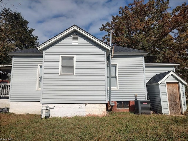 view of side of property featuring a lawn, central air condition unit, and a storage shed