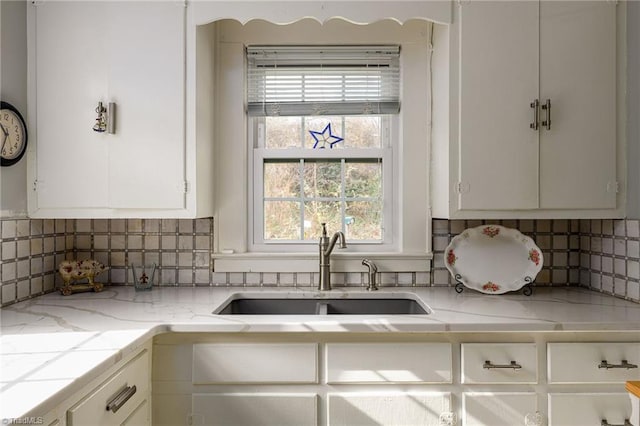 kitchen with a sink, tasteful backsplash, and white cabinetry