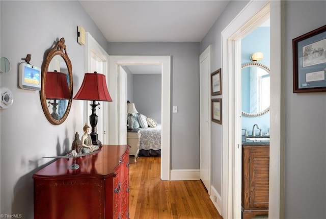 hallway with a sink, baseboards, and wood finished floors
