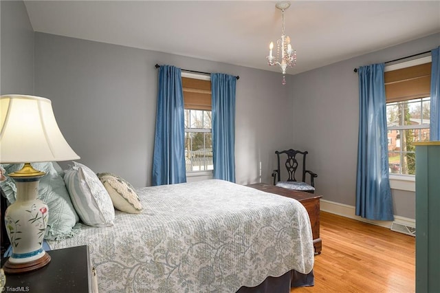 bedroom with an inviting chandelier, baseboards, and wood finished floors