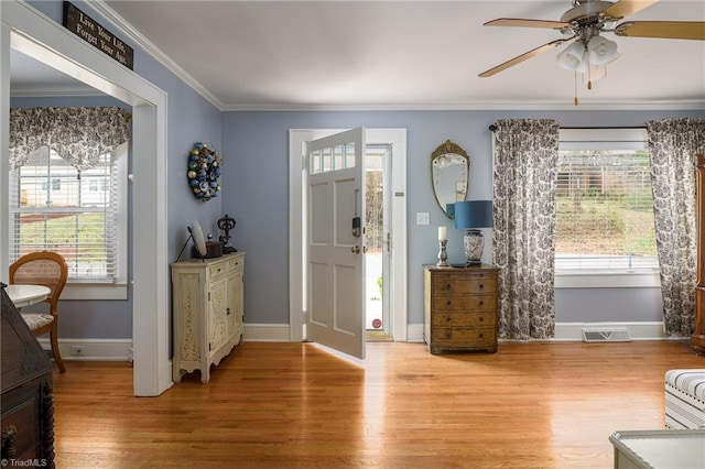 entrance foyer with light wood-style flooring, a healthy amount of sunlight, visible vents, and ornamental molding