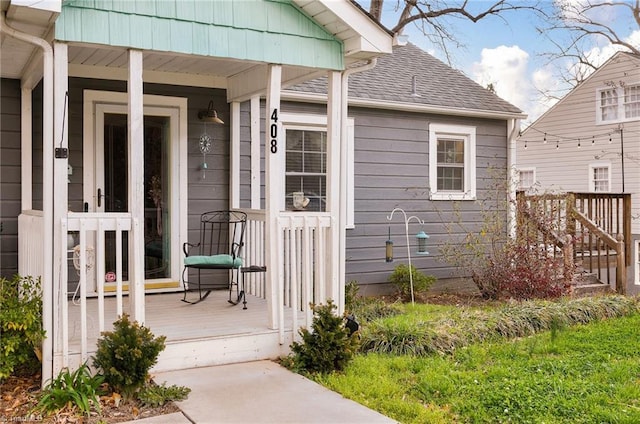entrance to property featuring covered porch and a shingled roof