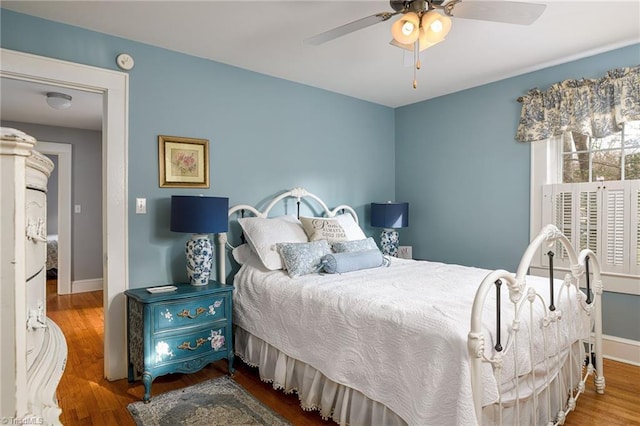 bedroom with ceiling fan, baseboards, and wood finished floors