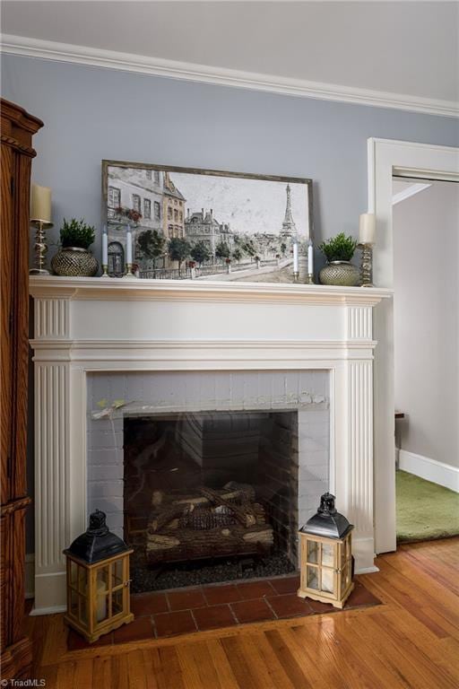 room details featuring a tiled fireplace, crown molding, baseboards, and wood finished floors