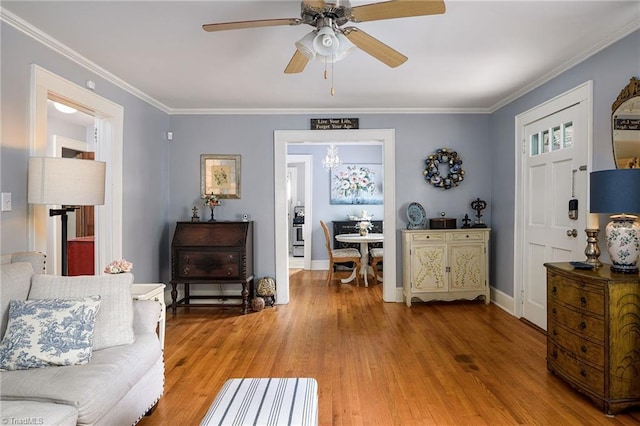 living area with ceiling fan with notable chandelier, light wood-style floors, and ornamental molding