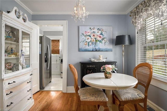 dining area featuring a healthy amount of sunlight, light wood-type flooring, crown molding, and an inviting chandelier
