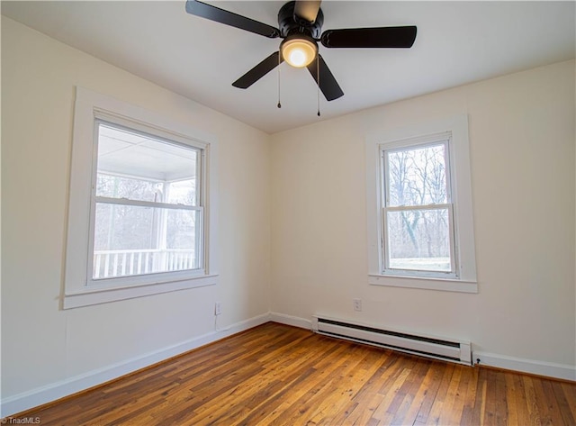 spare room with baseboards, baseboard heating, hardwood / wood-style flooring, and a healthy amount of sunlight