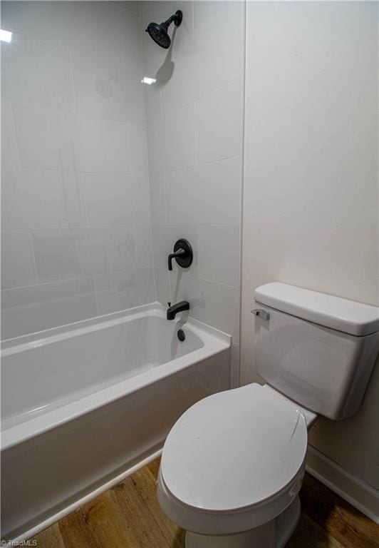 bathroom featuring washtub / shower combination, wood finished floors, and toilet