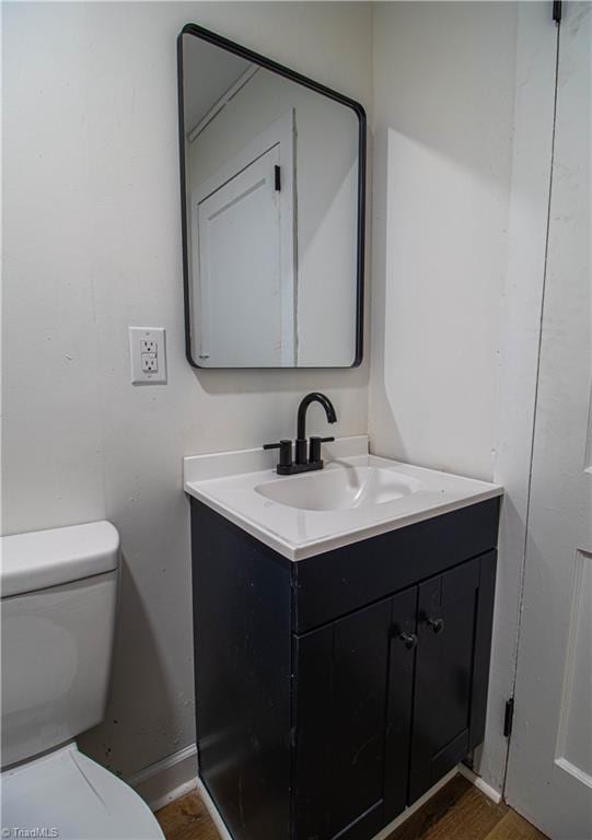 bathroom with toilet, wood finished floors, and vanity